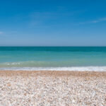 Summer blue sky ocean and pebble beach